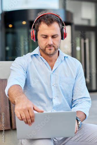 A man dressed respectably sits on the street with a laptop during a break in the office photo