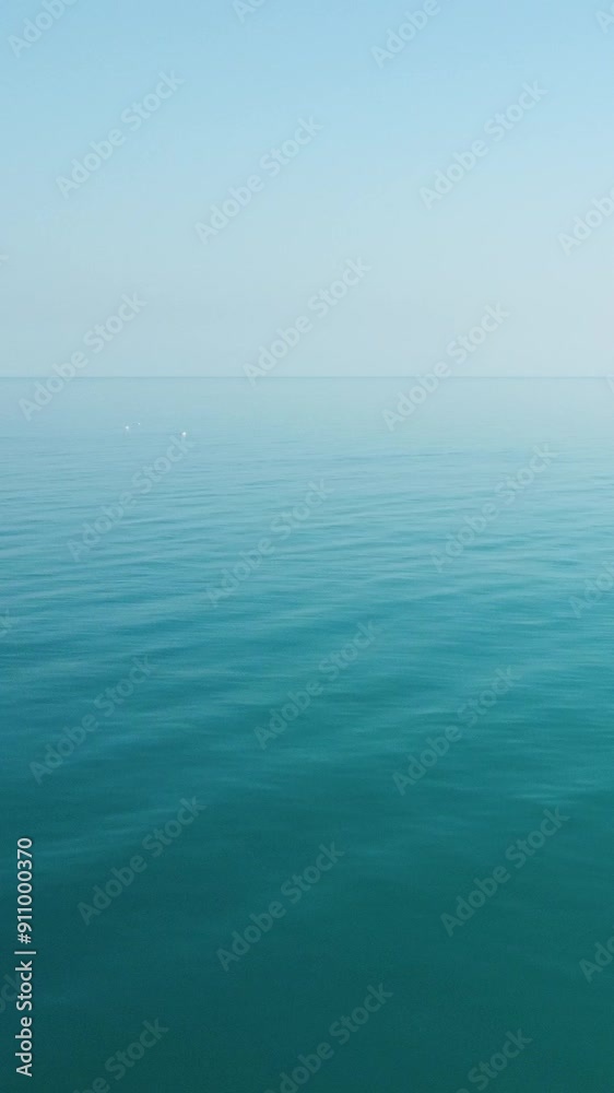 Aerial vertical view on calm azure sea. Small waves on water surface in motion blur. Nature summer ocean sea beach. Nobody. Weather and climate change. Holiday, vacation and travel idea. Aerial vertical view on calm azure sea. Small waves on water surface in motion blur. Nature summer ocean sea beach. Nobody. Weather and climate change. Holiday, vacation and travel idea.