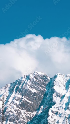 Vertical Time Lapse shot of clouds under the snow covered Himalayan mountain peaks during the day as seen from Khangsar village in Lahaul and Spiti district, Himachal Pradesh, India.  photo