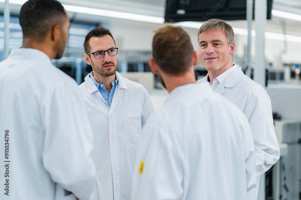 Technicians in lab coats discussing in electronics factory Technicians in lab coats discussing in electronics factory