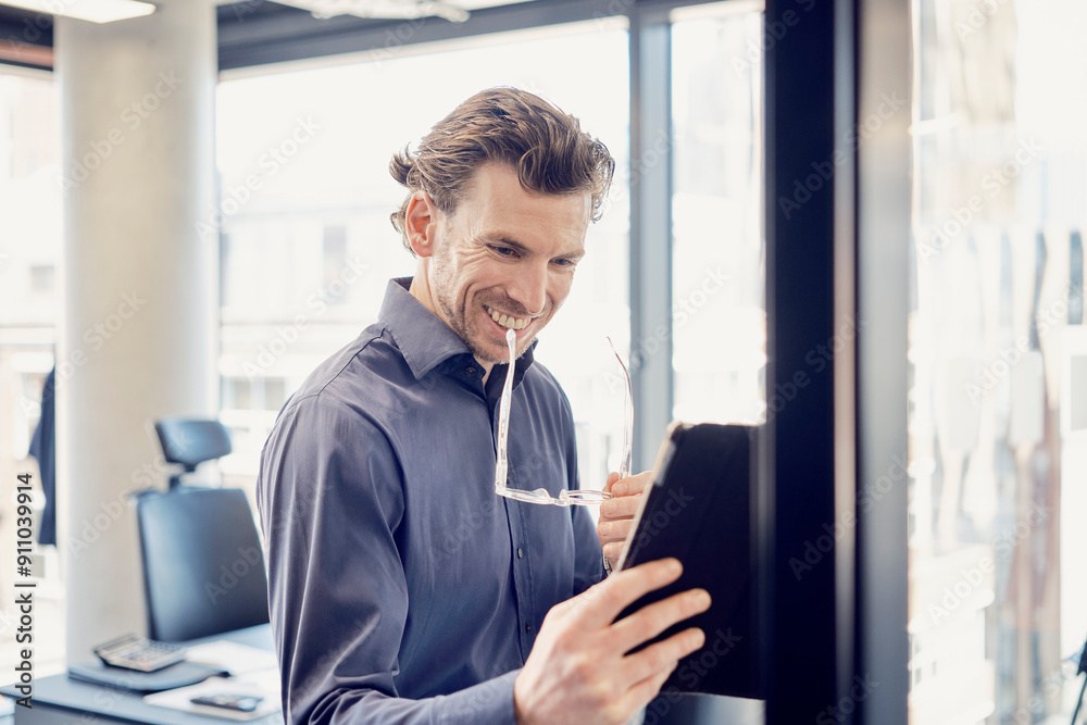 Smiling businessman doing video call through tablet PC at office Smiling businessman doing video call through tablet PC at office