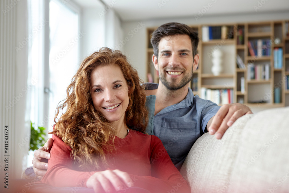 Happy smiling couple sitting on sofa at home Happy smiling couple sitting on sofa at home