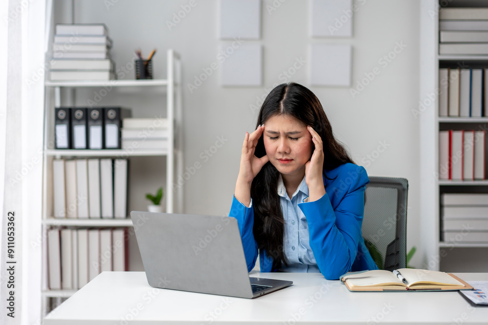 A woman is sitting at a desk with a laptop and a book A woman is sitting at a desk with a laptop and a book