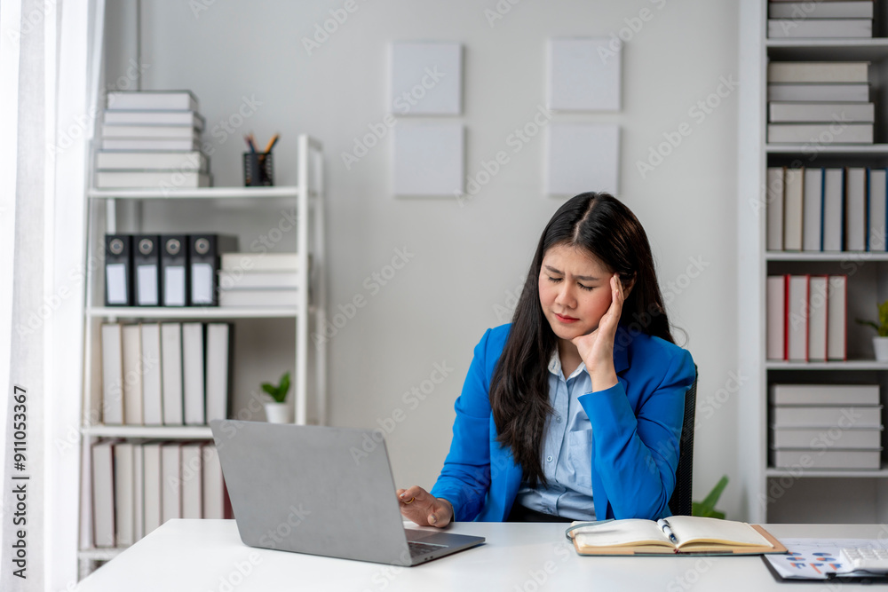A woman is sitting at a desk with a laptop and a book A woman is sitting at a desk with a laptop and a book
