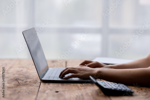 Close up of female hands while typing on laptop use calculator accountant 