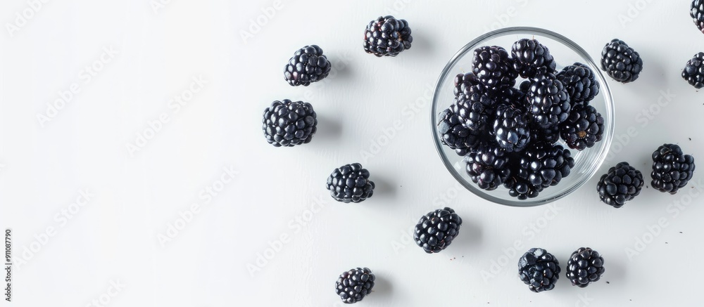 A white background with scattered blackberries in a glass providing space for text or images viewed from above horizontally. Copy space image. Place for adding text and design A white background with scattered blackberries in a glass providing space for text or images viewed from above horizontally. Copy space image. Place for adding text and design