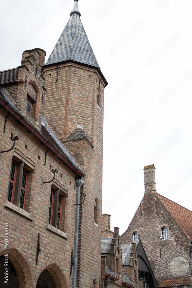 A brick building with multiple turrets and arched windows. The building has a medieval or renaissance style architecture. The building is surrounded by trees and shrubs. The sky is cloudy. A brick building with multiple turrets and arched windows. The building has a medieval or renaissance style architecture. The building is surrounded by trees and shrubs. The sky is cloudy.
