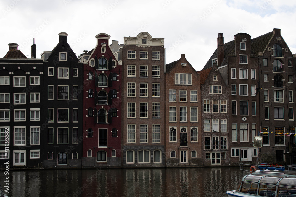 Fototapeta premium A brick building with multiple turrets and arched windows. The building has a medieval or renaissance style architecture. The building is surrounded by trees and shrubs. The sky is cloudy.