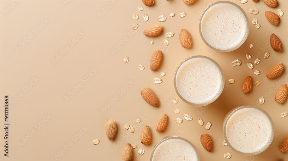 Top view of creamy almond milk in glass cups with scattered almonds and oats on a soft beige background, representing a healthy vegan and dairy-free alternative for breakfast or smoothies. Top view of creamy almond milk in glass cups with scattered almonds and oats on a soft beige background, representing a healthy vegan and dairy-free alternative for breakfast or smoothies.