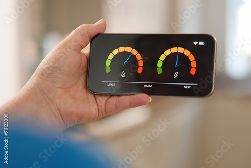 Person Checking Energy Consumption and Water Usage Levels on Smartphone Display