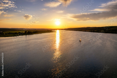 Einzelnes Segelboot bei Sonnenuntergang auf einem großen See photo