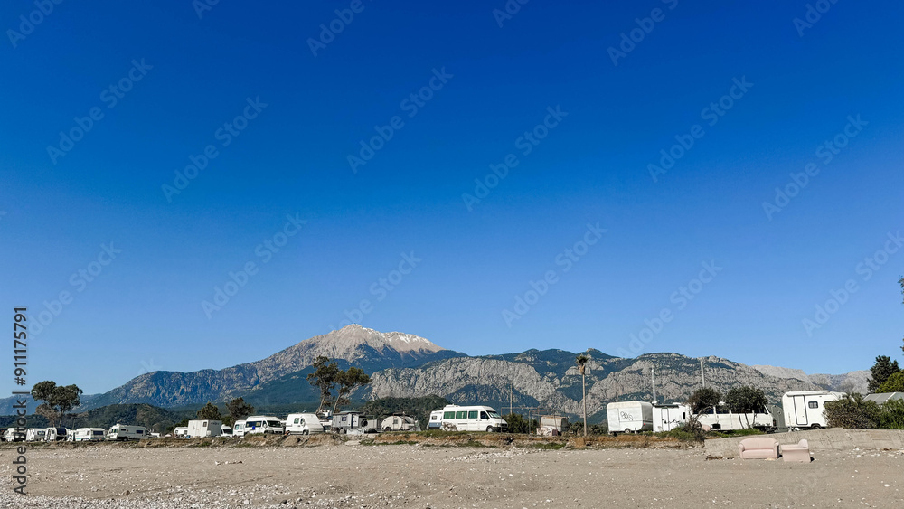 Summer sunny landscape. Parking of mobile homes, camping near the beach, with mountains in the background. Turkey, Antalya, Kemer. Summer sunny landscape. Parking of mobile homes, camping near the beach, with mountains in the background. Turkey, Antalya, Kemer.