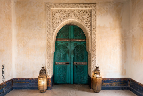 Turquoise green blue Moroccan arch door background, ornamental carved wood, interior, The Tower at Le Jardin Secret, Marrakech, Morocco. central composition with traditional decorative lanterns