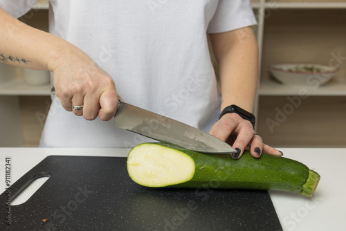 Woman cutting zucchini on a cutting board, close-up