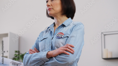 Woman standing proudly with a vote pin on her chest, fulfilling civic duty on election day