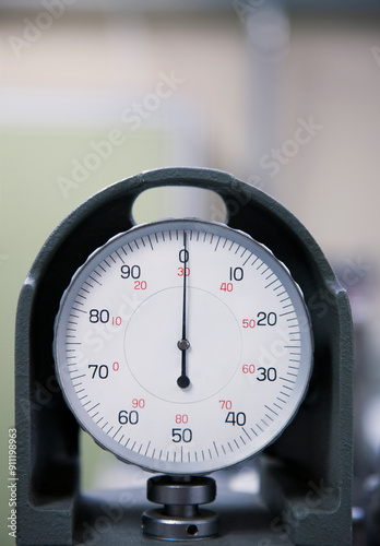 An industrial gauge in a factory, dial with numbers.