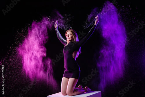 Obraz na płótnie Young slim woman posing on the big white cube with spread multicolored particles in the air w salonie
