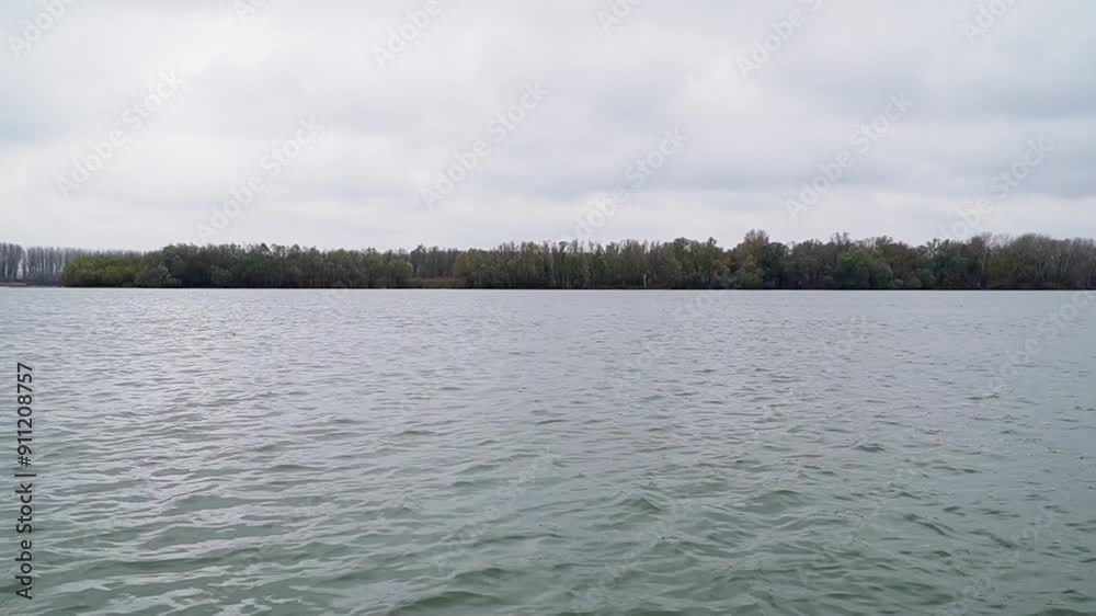 Beautiful clear river flows under cloudy sky in autumn bordered with trees Beautiful clear river flows under cloudy sky in autumn bordered with trees