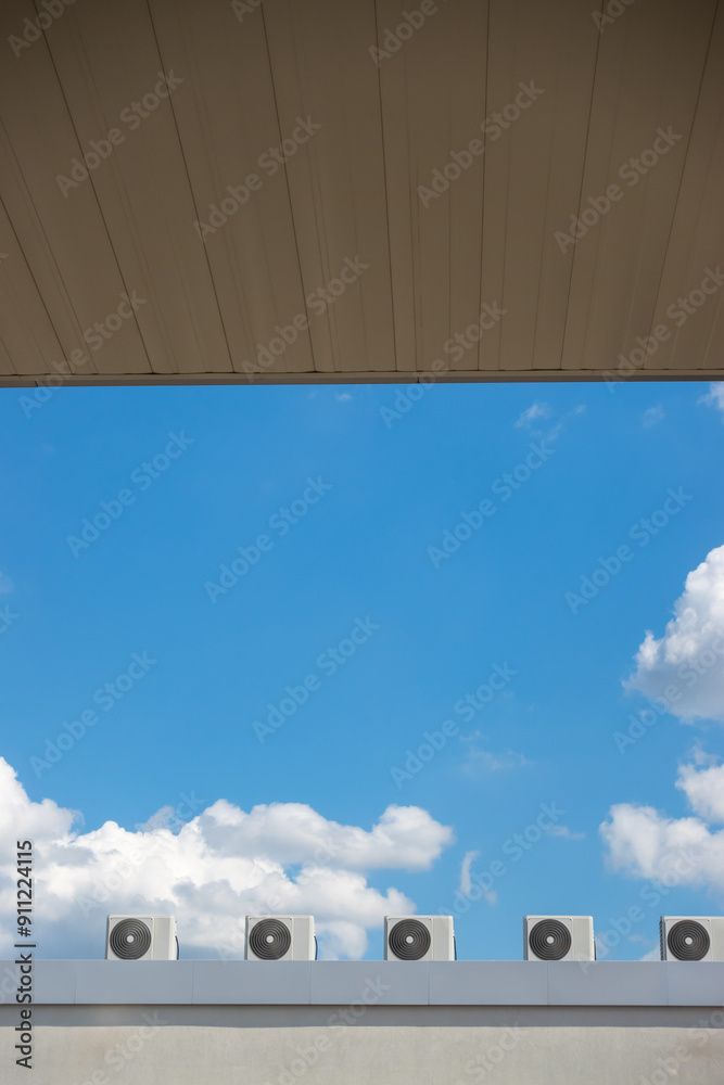 Several fans of an air conditioning system on the roof of a building against a blue sky background. The photo was taken on a sunny day.