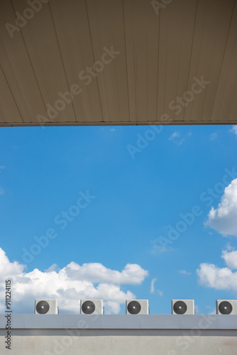 Obraz na płótnie Several fans of an air conditioning system on the roof of a building against a blue sky background. The photo was taken on a sunny day. w salonie