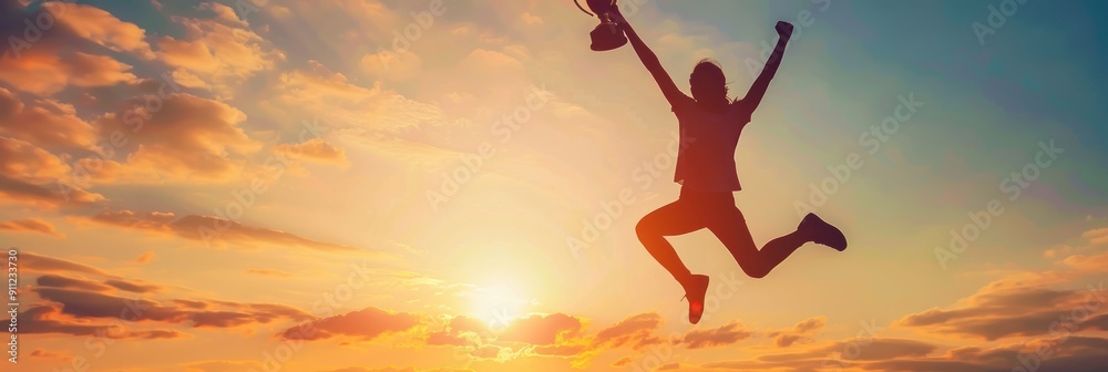 Naklejka premium Silhouette of a Woman Jumping with Trophy in Sunset Sky.
