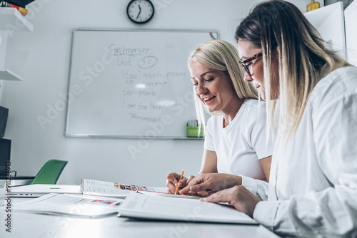 Two language learning students are focused on taking a test in their language class, showcasing their dedication to mastering a foreign tongue. 