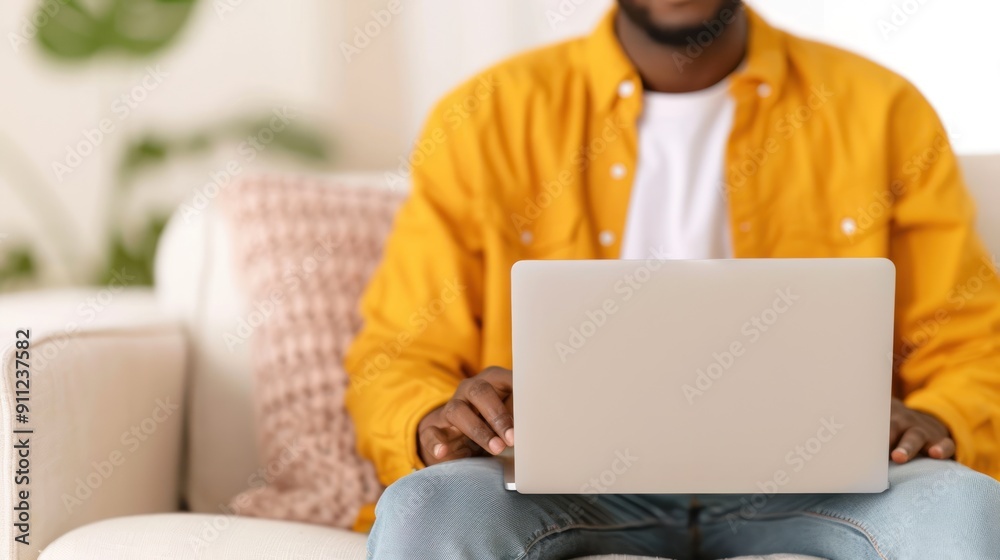 A man sitting on a couch with a laptop, filling out a detailed job application form online