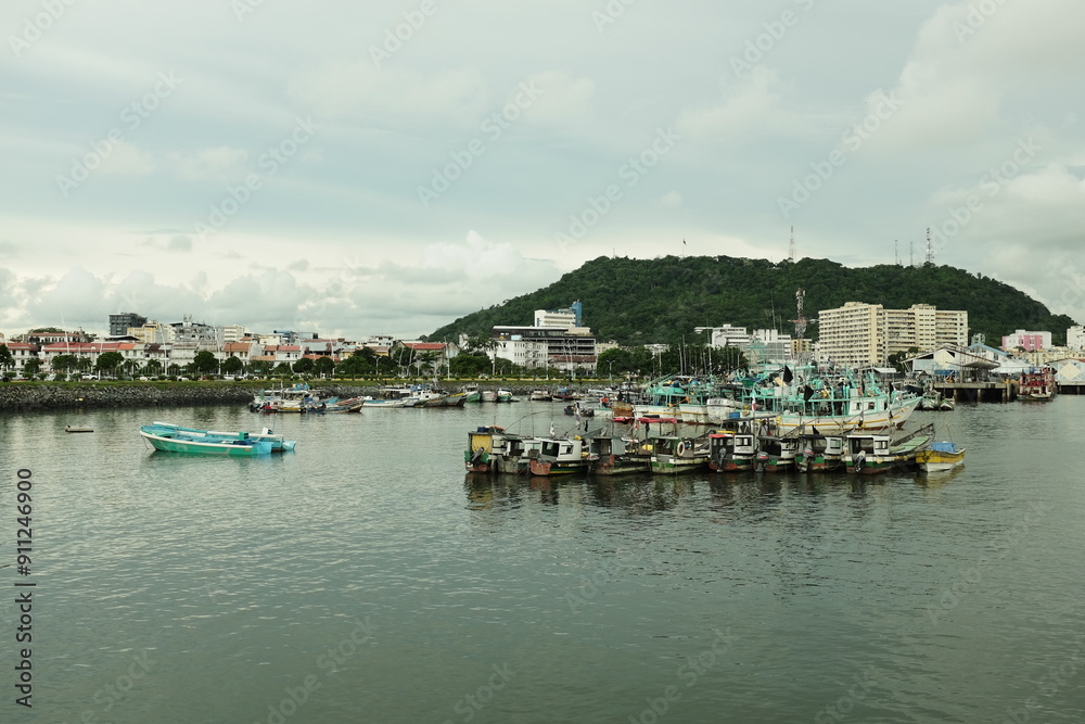 Embarcaciones de pesca anclados cerca a un poblado en aguas tranquilas con una montaña de fondo y edificios Embarcaciones de pesca anclados cerca a un poblado en aguas tranquilas con una montaña de fondo y edificios
