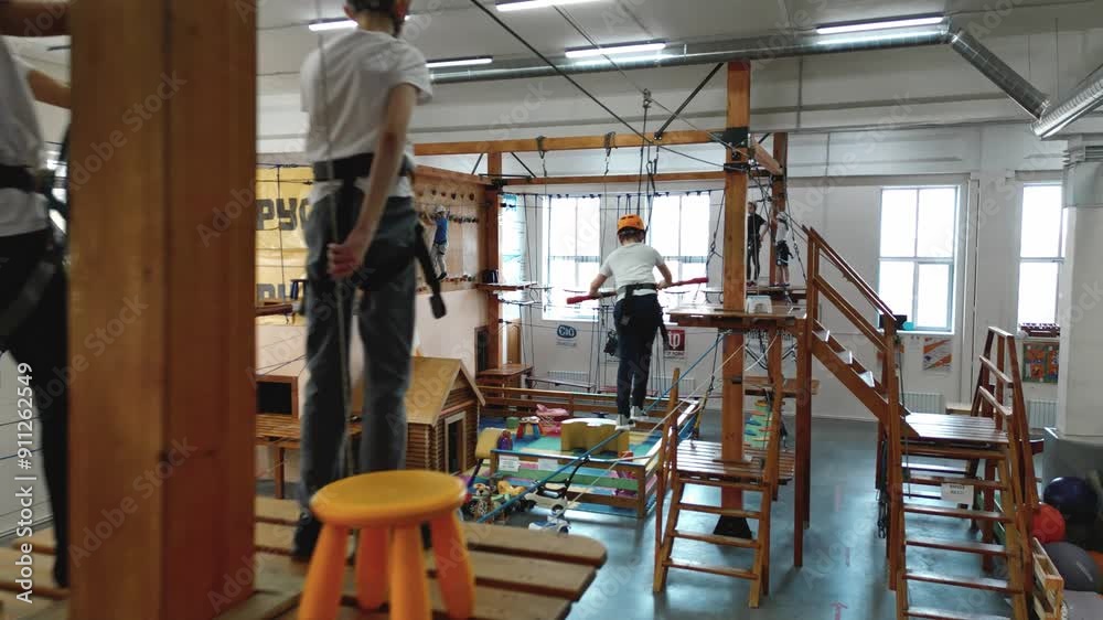 The camera flies on the road along an obstacle course in a rope park inside a room where 10-year-old boys and girls train. The application frame of the rope park. High quality 4k footage The camera flies on the road along an obstacle course in a rope park inside a room where 10-year-old boys and girls train. The application frame of the rope park. High quality 4k footage