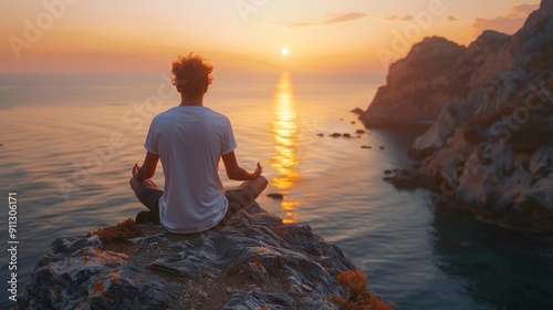 A young man practicing yoga on a cliff overlooking the sea at sunrise