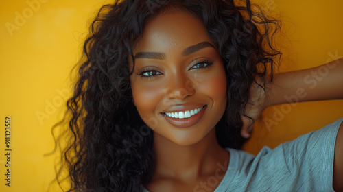 Portrait of Smiling Attractive Woman with Curly Hair Against Yellow Background