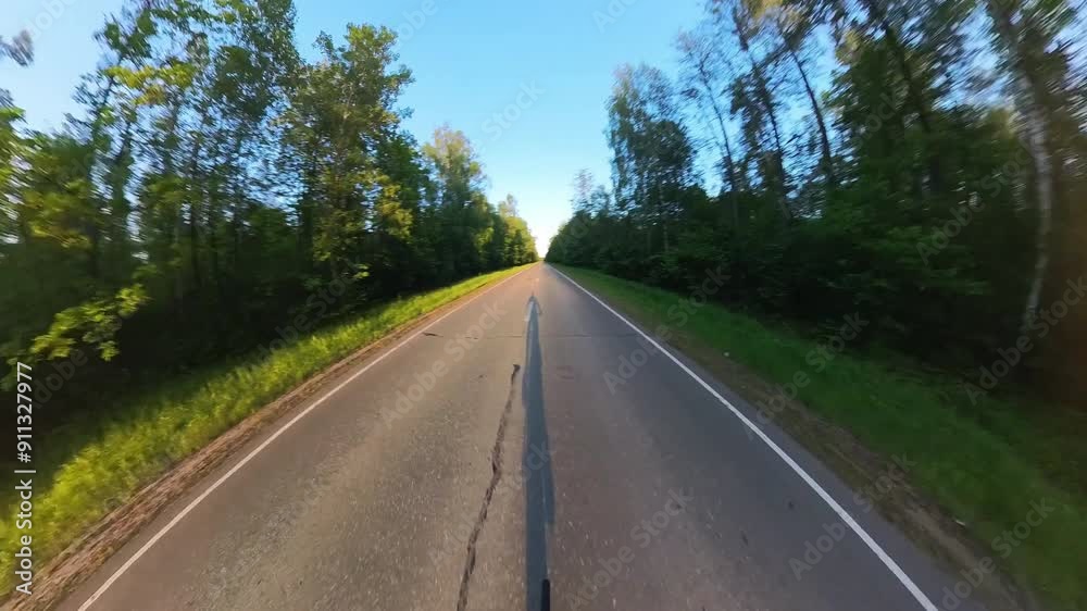 Young man cycling on the asphalt empty road at sunset Young man cycling on the asphalt empty road at sunset