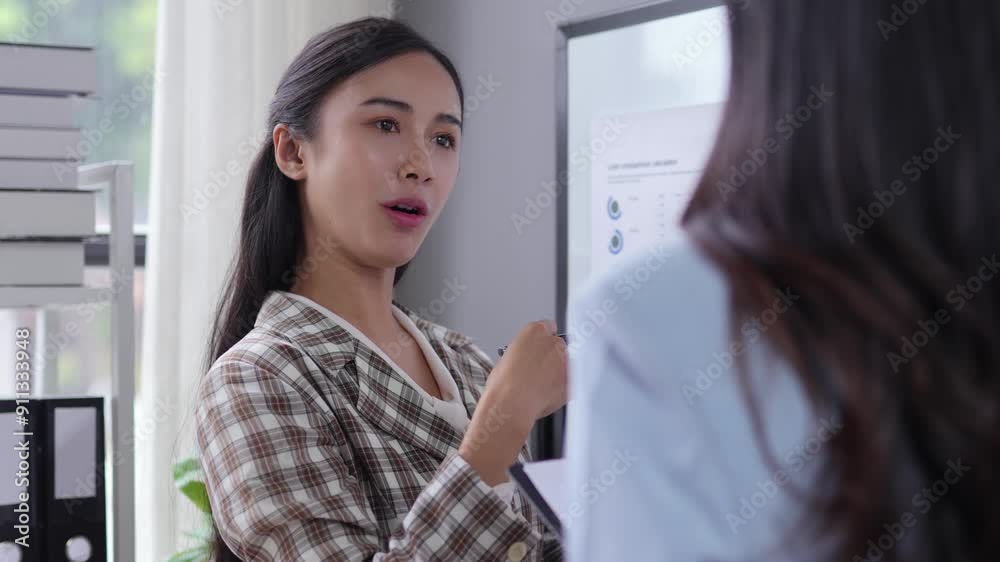 Confident businesswoman presenting financial data charts to colleague in a modern office, using a whiteboard for visual aid Confident businesswoman presenting financial data charts to colleague in a modern office, using a whiteboard for visual aid