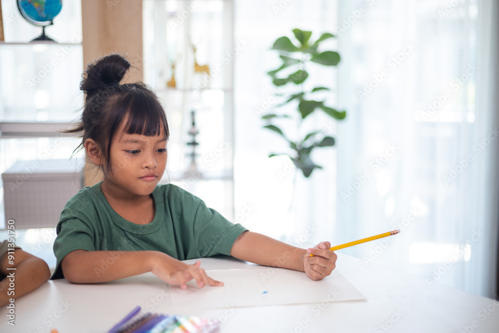A young girl is sitting at a table with a pencil and a piece of paper in her hand. She is practicing drawing and coloring, honing her skills at home. A young girl is sitting at a table with a pencil and a piece of paper in her hand. She is practicing drawing and coloring, honing her skills at home.
