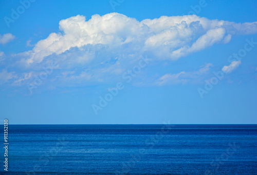 Obraz na płótnie spokojne, niebieskie morze z niebieskim niebiem i białymi, pierzastymi chmurami, morski krajobraz, pogodne niebo nad morzem, horyzont, blue sea with blue sky, sea landscape, horizon, w salonie