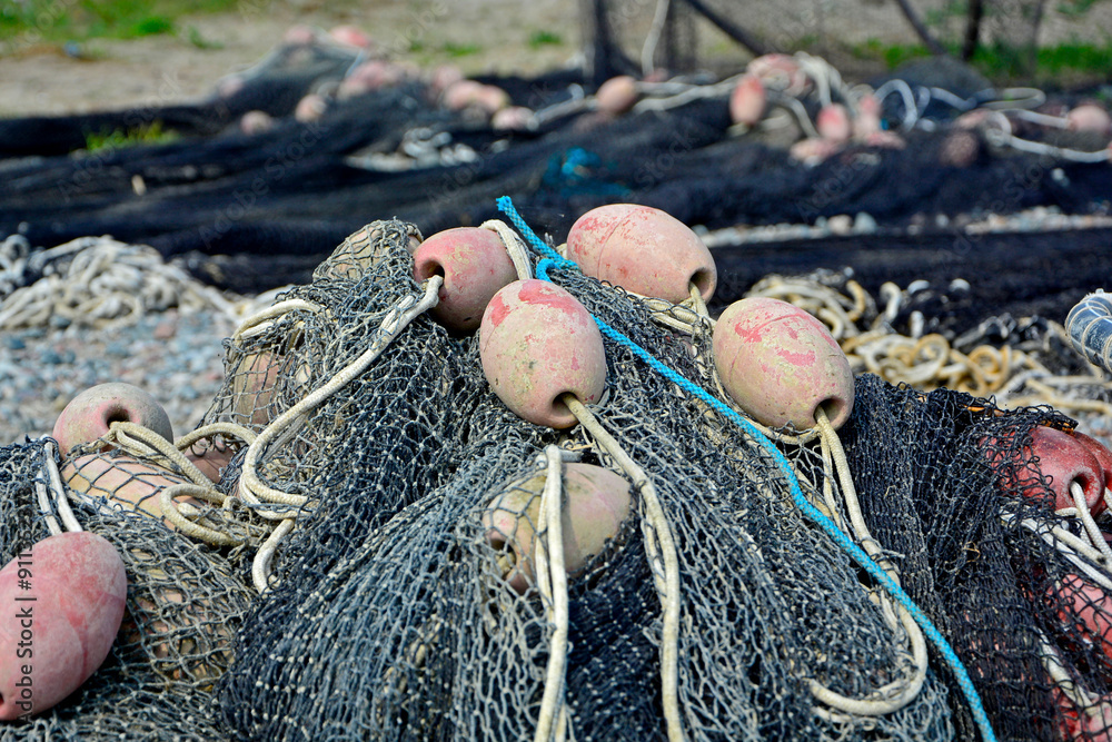 sieć rybacka z pływakami na brzegu, suszące sie na brzegu sieci rybackie z pływakami, fishing net on the shore, fishing net drying, Fishing net in the harbor, nets and floats are dried on the shore.