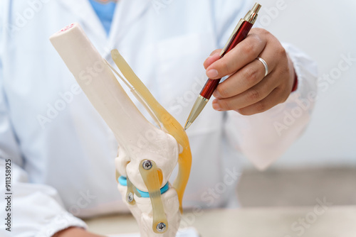 A doctor uses a knee joint model to demonstrate anatomy, diagnose conditions like osteoarthritis, and discuss treatment options, including surgery and therapy, with a patient in a clinical setting. photo