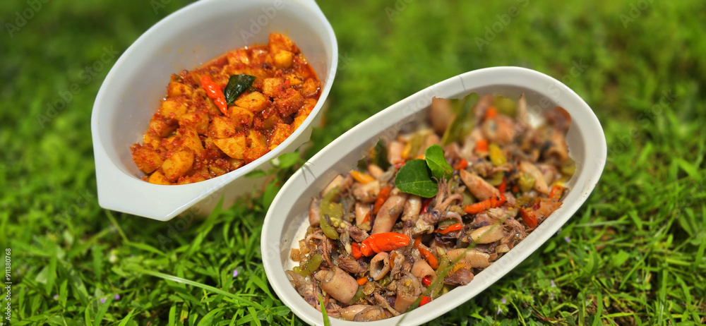 sauteed salty squid with black ink sauce with spicy seasoning called tumis cumi asin, is local Indonesian homemade cooking to include chili, ginger, and lime leaf served in a bowl sauteed salty squid with black ink sauce with spicy seasoning called tumis cumi asin, is local Indonesian homemade cooking to include chili, ginger, and lime leaf served in a bowl