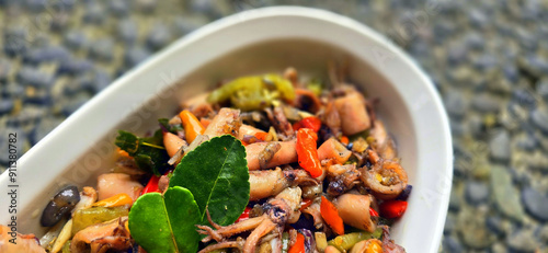 sauteed salty squid with black ink sauce with spicy seasoning called tumis cumi asin, is local Indonesian homemade cooking to include chili, ginger, and lime leaf served in a bowl photo