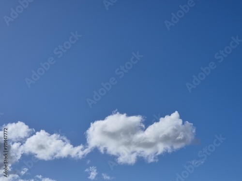 Summer white fluffy cumulus clouds in the deep blue sky