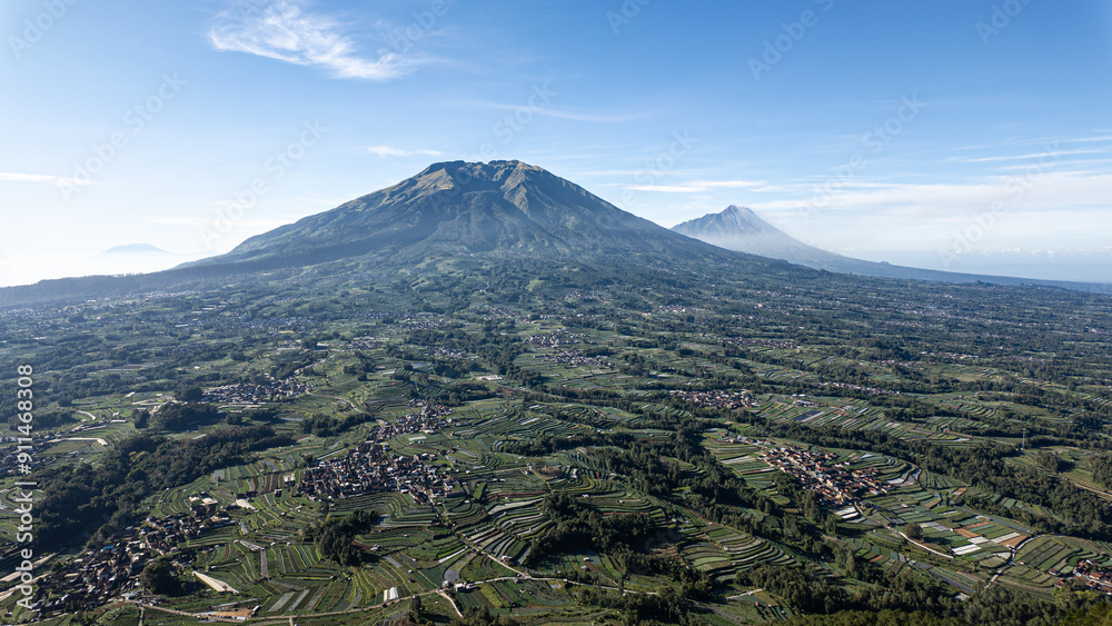 Views of Mount Merbabu and Mount Merapi in the distance from peak of Mount Andong with villages and farms on the mountain slopes Views of Mount Merbabu and Mount Merapi in the distance from peak of Mount Andong with villages and farms on the mountain slopes