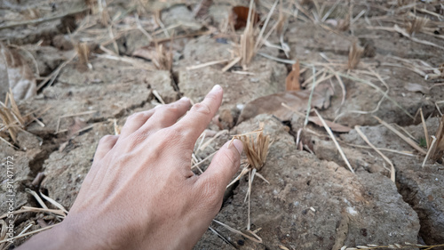 Fotografi Someone hand try to touch over cracked soil background