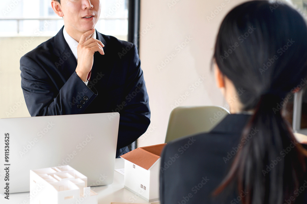 住宅模型を使い会議をする若い男女の会社員
