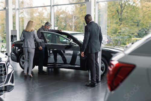 Car dealership employee presents vehicle potential buyer photo