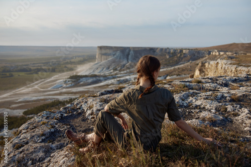 Woman sitting on cliff edge overlooking valley and mountains with a sense of adventure and wanderlust photo