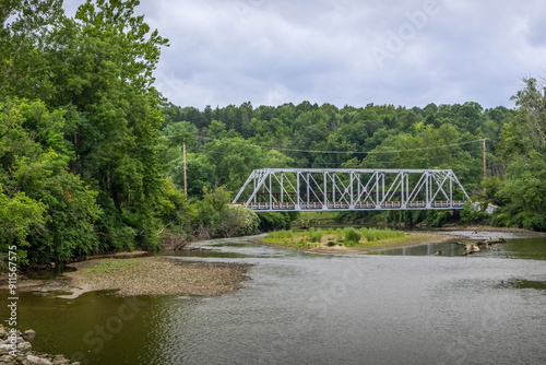 Canvas-taulu The metal bridge across Cuyahoga river on Ohio, with the automotive road and scenic nature forest around