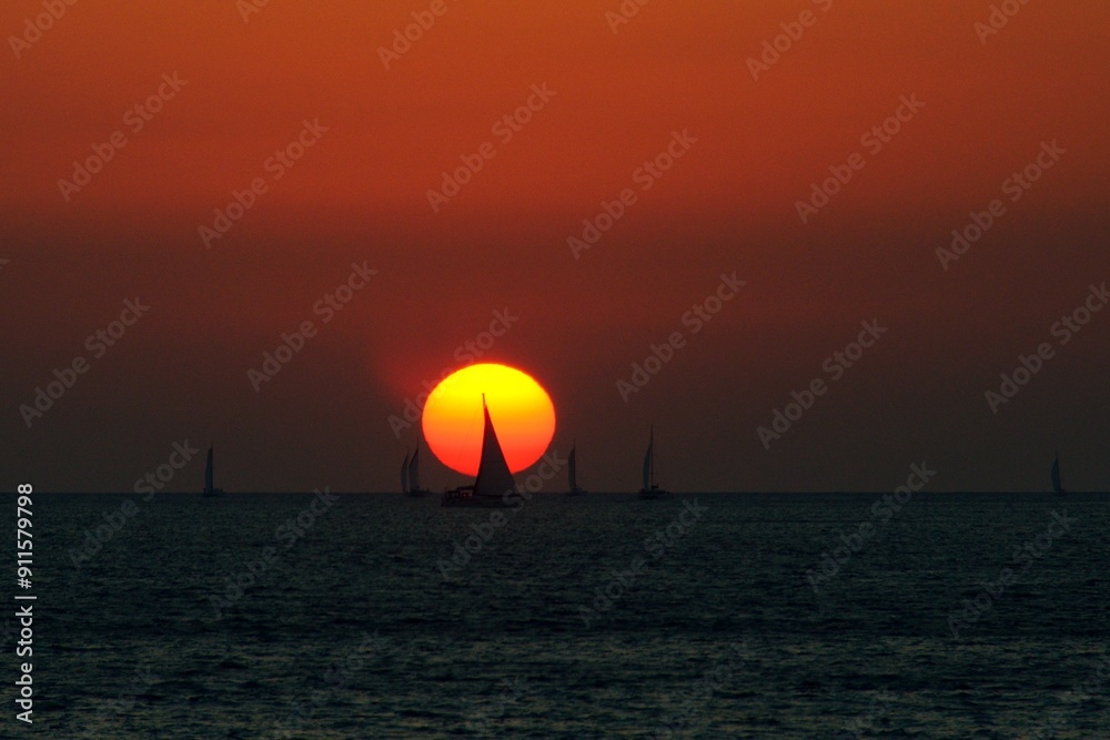 Barcos en el horizonte durante la puesta de sol en Vlichada, isla de Santorini, Grecia Barcos en el horizonte durante la puesta de sol en Vlichada, isla de Santorini, Grecia