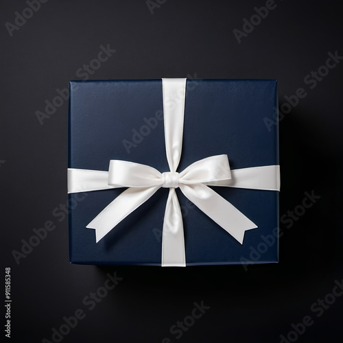 Dark blue  giftbox with milky-white ribbon bow on isolated black background with empty space