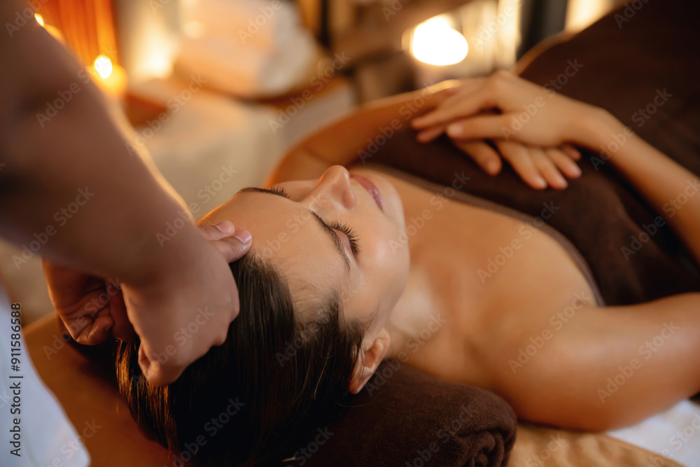 Fototapeta premium Caucasian woman enjoying relaxing anti-stress head massage and pampering facial beauty skin recreation leisure in warm candle lighting ambient salon spa in luxury resort or hotel. Quiescent