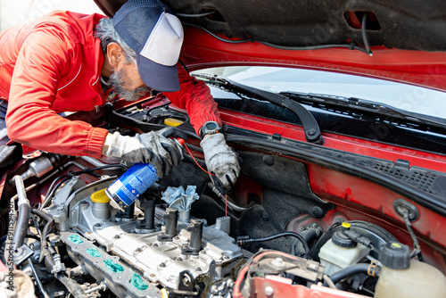 Adult man, knowledgeable about automobiles, works on his car